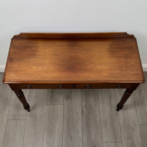 fig 8. A Victorian mahogany writing table featuring two frieze drawers with brass ring handles and four turned legs.