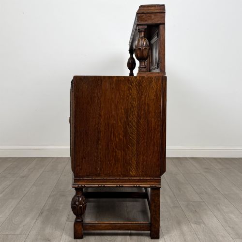 fig 3. A dark carved oak sideboard featuring a raised gallery back, geometric octagonal panel doors, two central drawers with brass handles, and bulbous turned legs.