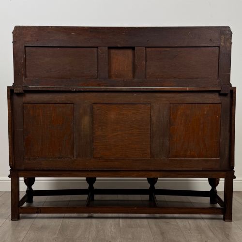 fig 5. A dark carved oak sideboard featuring a raised gallery back, geometric octagonal panel doors, two central drawers with brass handles, and bulbous turned legs.