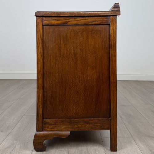 fig 2. A twentieth-century dark oak chest of drawers featuring three drawers with geometric panel moulding, decorative drop handles, and shaped bracket feet.