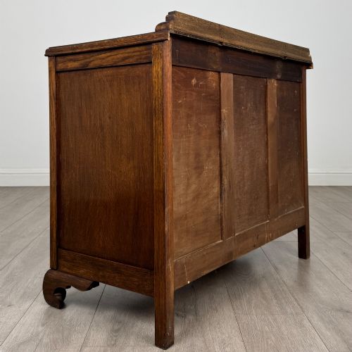 fig 3. A twentieth-century dark oak chest of drawers featuring three drawers with geometric panel moulding, decorative drop handles, and shaped bracket feet.