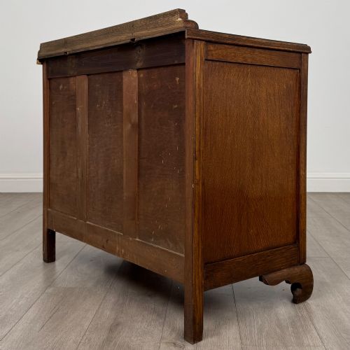 fig 5. A twentieth-century dark oak chest of drawers featuring three drawers with geometric panel moulding, decorative drop handles, and shaped bracket feet.