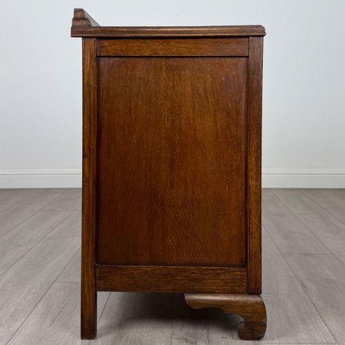 fig 6. A twentieth-century dark oak chest of drawers featuring three drawers with geometric panel moulding, decorative drop handles, and shaped bracket feet.
