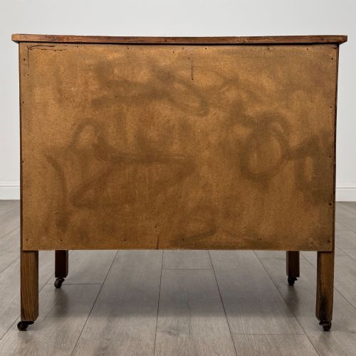 fig 5. An early 20th-century golden oak side cabinet featuring a top drawer with ornate metal drop handles above a central panelled cupboard door on square legs with castors.