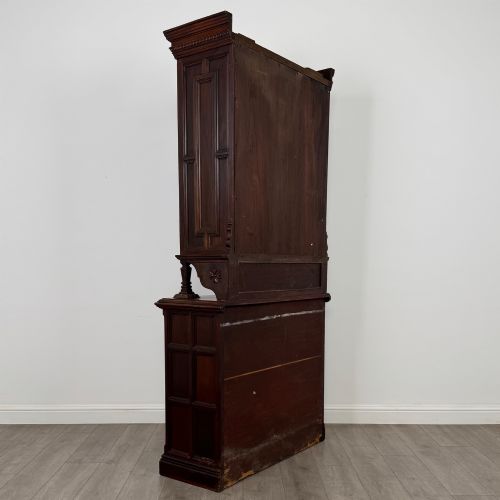 fig 4. A nineteenth-century dark mahogany glazed bookcase featuring a carved swan neck pediment, twin arched glass upper doors, and a lower two-door cabinet with carved panels.