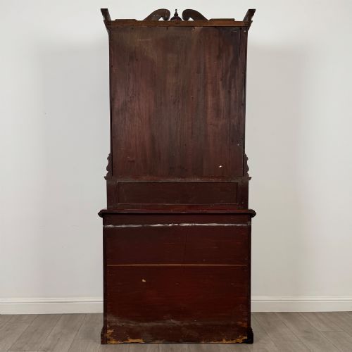 fig 5. A nineteenth-century dark mahogany glazed bookcase featuring a carved swan neck pediment, twin arched glass upper doors, and a lower two-door cabinet with carved panels.