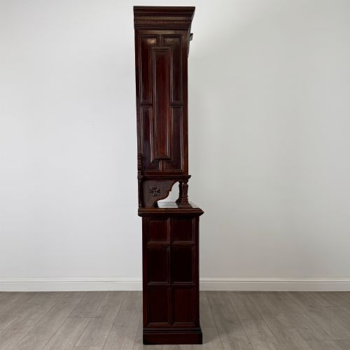fig 7. A nineteenth-century dark mahogany glazed bookcase featuring a carved swan neck pediment, twin arched glass upper doors, and a lower two-door cabinet with carved panels.