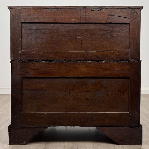 fig 4. A seventeenth-century William and Mary oak chest of drawers featuring four drawers with brass escutcheons and drop handles raised on bracket feet.