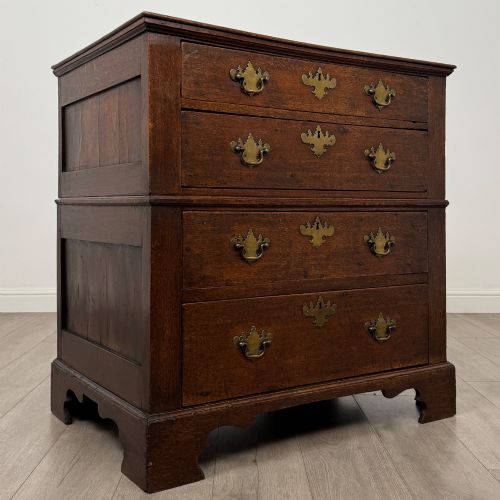 fig 7. A seventeenth-century William and Mary oak chest of drawers featuring four drawers with brass escutcheons and drop handles raised on bracket feet.