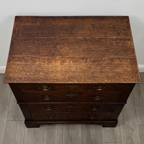 fig 8. A seventeenth-century William and Mary oak chest of drawers featuring four drawers with brass escutcheons and drop handles raised on bracket feet.