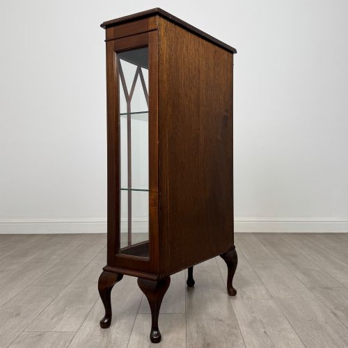 fig 3. An antique mahogany display cabinet featuring a single door with geometric astragal glazing bars, glass shelves, and cabriole legs.