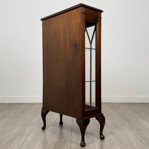 fig 5. An antique mahogany display cabinet featuring a single door with geometric astragal glazing bars, glass shelves, and cabriole legs.
