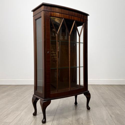 fig 7. An antique mahogany display cabinet featuring a single door with geometric astragal glazing bars, glass shelves, and cabriole legs.