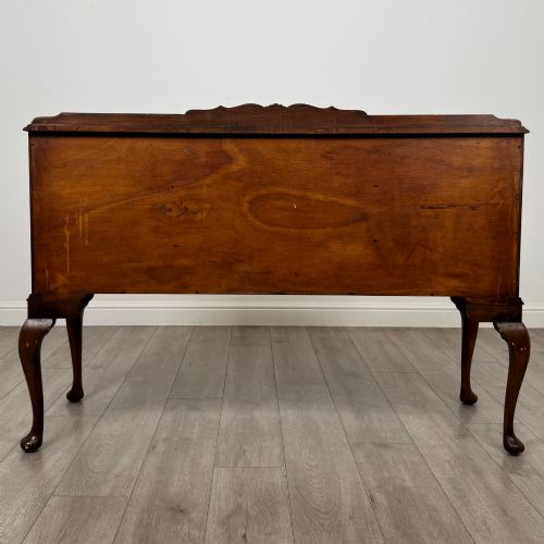 fig 5. A 20th-century burr walnut sideboard featuring three central bowfront drawers flanked by cupboard doors, supported on carved cabriole legs.