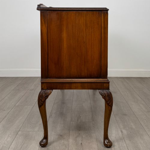fig 7. A 20th-century burr walnut sideboard featuring three central bowfront drawers flanked by cupboard doors, supported on carved cabriole legs.