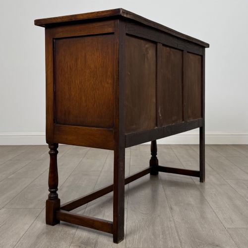 fig 4. A dark oak cupboard featuring two door panels with carved Gothic arch motifs, wooden turn latches, and turned front legs connected by a perimeter stretcher.