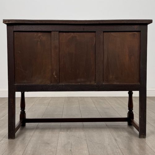 fig 5. A dark oak cupboard featuring two door panels with carved Gothic arch motifs, wooden turn latches, and turned front legs connected by a perimeter stretcher.