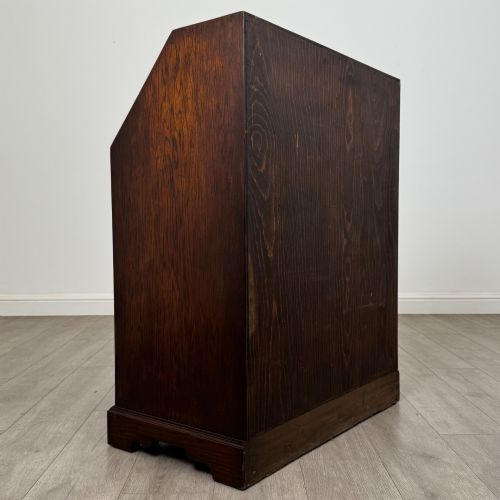 fig 4. A dark oak Jacobean style slant-front bureau featuring geometric inlaid panels and four drawer fronts with turned wooden knobs.