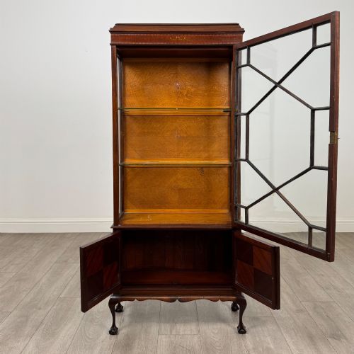 fig 1. An early 20th-century mahogany glazed display cabinet featuring geometric astragal doors, marquetry inlaid lower cupboards, and cabriole legs.