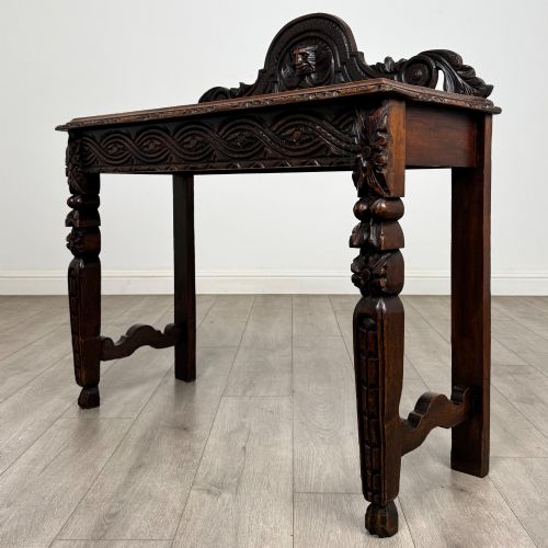 fig 1. A dark carved oak Victorian side table featuring a sculpted mask upstand gallery, relief-carved frieze, and detailed carved legs.