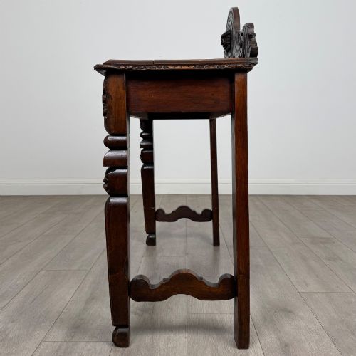 fig 2. A dark carved oak Victorian side table featuring a sculpted mask upstand gallery, relief-carved frieze, and detailed carved legs.