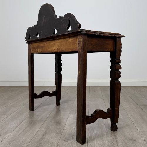 fig 5. A dark carved oak Victorian side table featuring a sculpted mask upstand gallery, relief-carved frieze, and detailed carved legs.