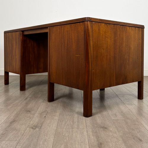 fig 5. A large mid-20th century mahogany pedestal desk featuring two sets of drawers with brass drop handles and a central kneehole.