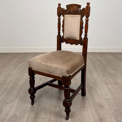 fig 1. A set of four 19th-century Victorian carved oak dining chairs featuring beige upholstered seats, turned legs, and detailed crest carved backrests.