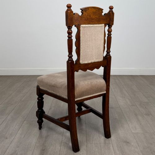 fig 2. A set of four 19th-century Victorian carved oak dining chairs featuring beige upholstered seats, turned legs, and detailed crest carved backrests.