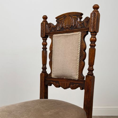 fig 3. A set of four 19th-century Victorian carved oak dining chairs featuring beige upholstered seats, turned legs, and detailed crest carved backrests.