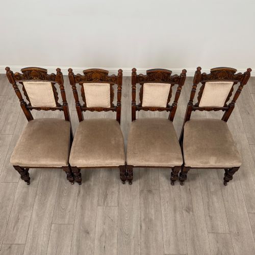 fig 6. A set of four 19th-century Victorian carved oak dining chairs featuring beige upholstered seats, turned legs, and detailed crest carved backrests.