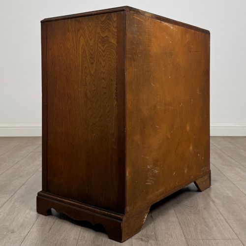 fig 3. A dark oak chest of four drawers decorated with carved floral rosettes and dark metal drop ring handles.