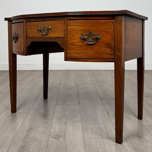 fig 1. An 18th-century Georgian mahogany writing table with a bow-front top, three drawers fitted with brass handles, supported by square tapered legs.
