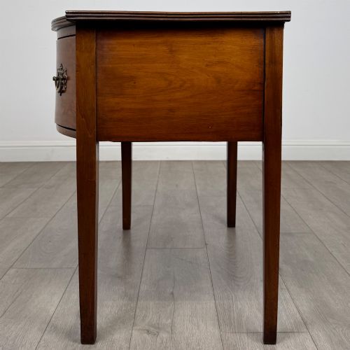 fig 2. An 18th-century Georgian mahogany writing table with a bow-front top, three drawers fitted with brass handles, supported by square tapered legs.