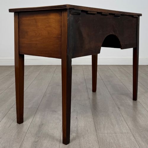 fig 3. An 18th-century Georgian mahogany writing table with a bow-front top, three drawers fitted with brass handles, supported by square tapered legs.