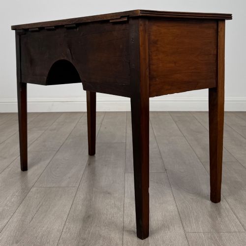 fig 5. An 18th-century Georgian mahogany writing table with a bow-front top, three drawers fitted with brass handles, supported by square tapered legs.
