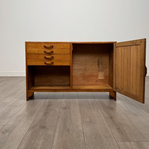 fig 1. A compact golden oak sideboard featuring four shallow drawers on the left, an open shelf below, and a slatted single door cabinet on the right.