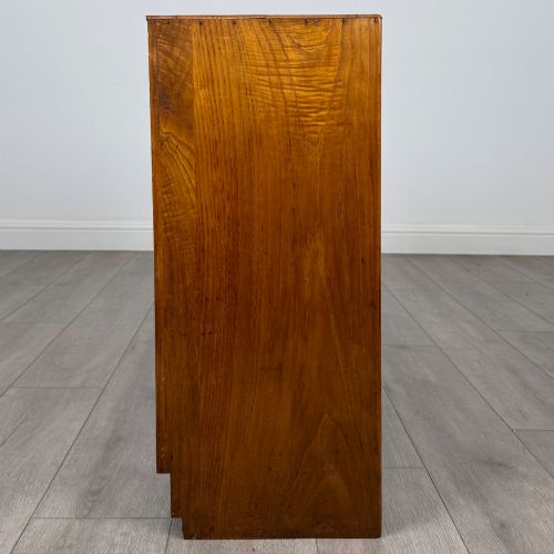 fig 7. A compact golden oak sideboard featuring four shallow drawers on the left, an open shelf below, and a slatted single door cabinet on the right.