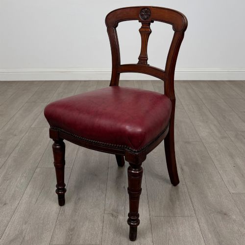 fig 1. A set of four 19th-century mahogany dining chairs featuring carved open backs, dark red leather upholstered seats with stud trim, and turned front legs.