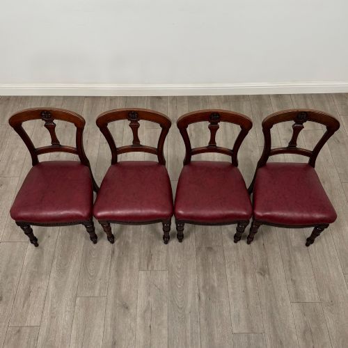 fig 6. A set of four 19th-century mahogany dining chairs featuring carved open backs, dark red leather upholstered seats with stud trim, and turned front legs.