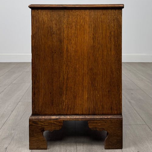 fig 2. An antique oak chest of drawers featuring two short over three long drawers with brass swan-neck handles and shaped bracket feet.