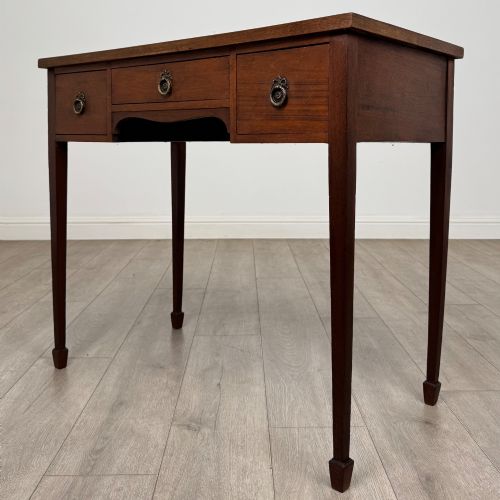 fig 1. An early 20th-century mahogany writing table featuring three drawers with decorative brass ring handles and square tapered legs.