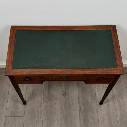 fig 8. An early 20th-century mahogany writing table featuring three drawers with decorative brass ring handles and square tapered legs.