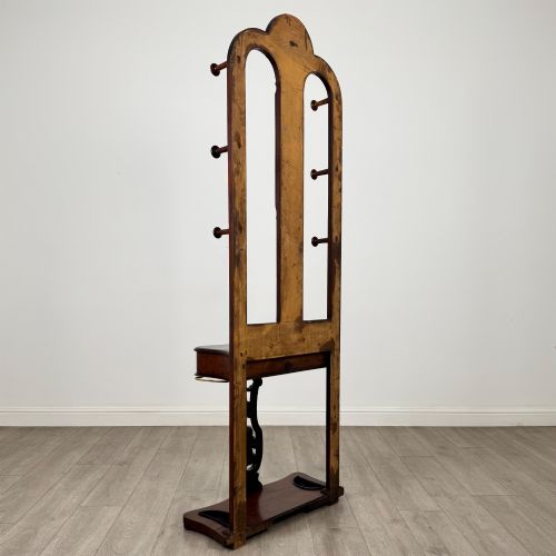fig 3. A freestanding Victorian mahogany hall stand featuring turned coat pegs, a narrow central mirror panel, a small shelf, and an umbrella holder base.