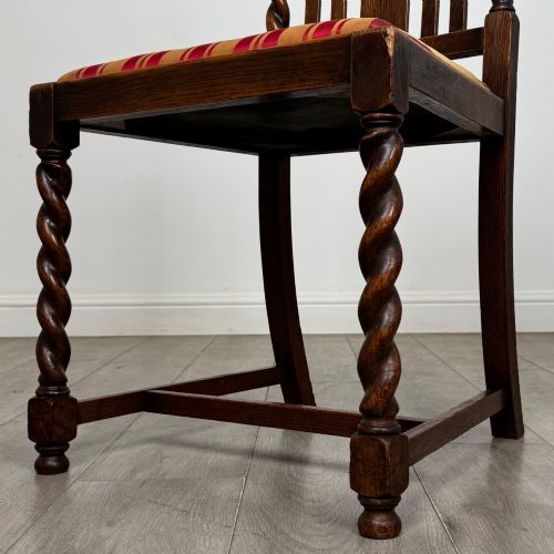 fig 5. A set of six dark oak dining chairs featuring barley twist legs and stretchers with red and gold striped fabric seats.