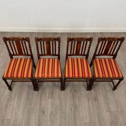 fig 7. A set of six dark oak dining chairs featuring barley twist legs and stretchers with red and gold striped fabric seats.