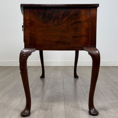 fig 2. An Edwardian mahogany writing table with cabriole legs, carved knee detailing, three drawers with ornate brass handles, and a central arched kneehole.