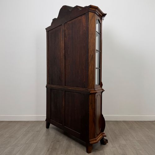 fig 6. A Dutch walnut display cabinet featuring a carved bonnet-top pediment, multi-pane glazed doors, and a lower chest of drawers on carved claw-and-ball feet.