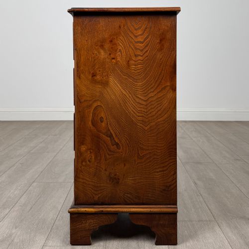 fig 2. A small 20th-century serpentine chest of drawers with four drawers featuring burr walnut veneer, brass drop handles, and bracket feet.