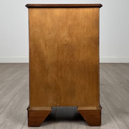 fig 4. A small 20th-century serpentine chest of drawers with four drawers featuring burr walnut veneer, brass drop handles, and bracket feet.